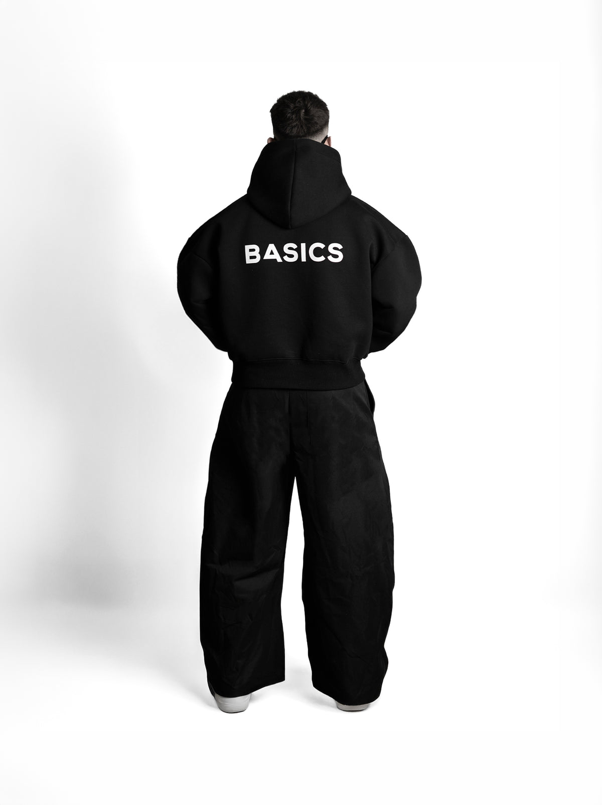 The Founders Hoodie negro puesta, de espaldas, con el logo BASICS